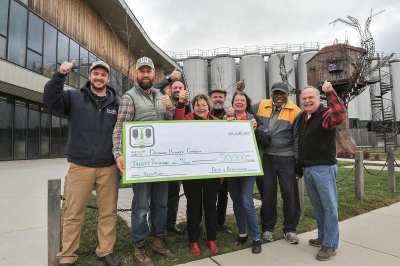 At the brewery in Milton, Mark Carter, director of Dogfish Head's Beer & Benevolence program, presents the company's $30,000 pledge to the Delaware Botanic Gardens. Shown are (l-r) Tyler Hammond, director of operations for Envirotech Environmental Consulting; Carter; and Delaware Botanic Gardens leaders Gregg Tepper, Sheryl Swed, Henry DeWitt, Janet Point, Peter Carter and Raymond Sander. SUBMITTED PHOTO
